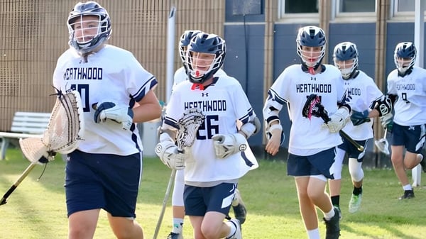 Eine Gruppe junger Athleten in Lacrosse-Uniformen steht auf dem Sportgelände der Heathwood Hall Episcopal School.