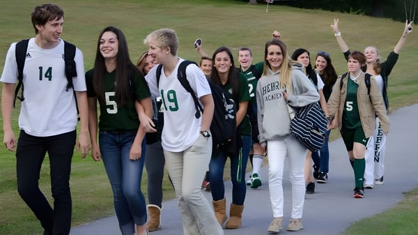 Eine Gruppe von Schülerinnen und Schülern steht gemeinsam auf einem Grasfeld auf dem Campus der Hebron Academy.