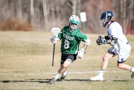 Zwei Spielerinnen in Lacrosse-Uniformen treten auf dem Spielfeld der Hebron Academy gegeneinander an.