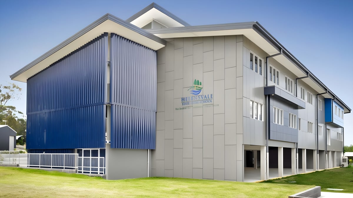 Das moderne mehrstöckige Gebäude der Helensvale State High School mit grauen und blauen Außenpaneelen und einer Rasenfläche im Vordergrund.
