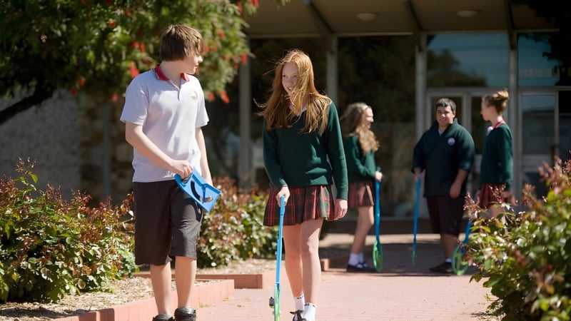Eine Gruppe Schüler der Henley High School geht auf einem Weg, der von grüner Vegetation umgeben ist.