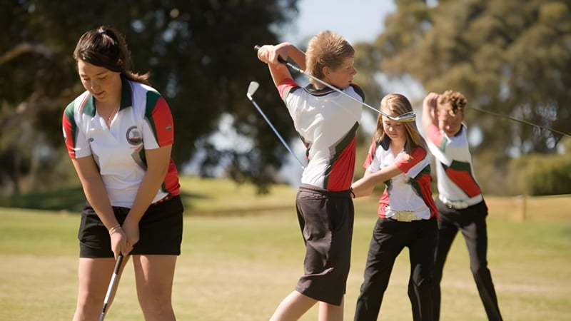 Eine Gruppe Schüler in Sportkleidung steht auf einem Sportplatz der Henley High School bei klarem Himmel.