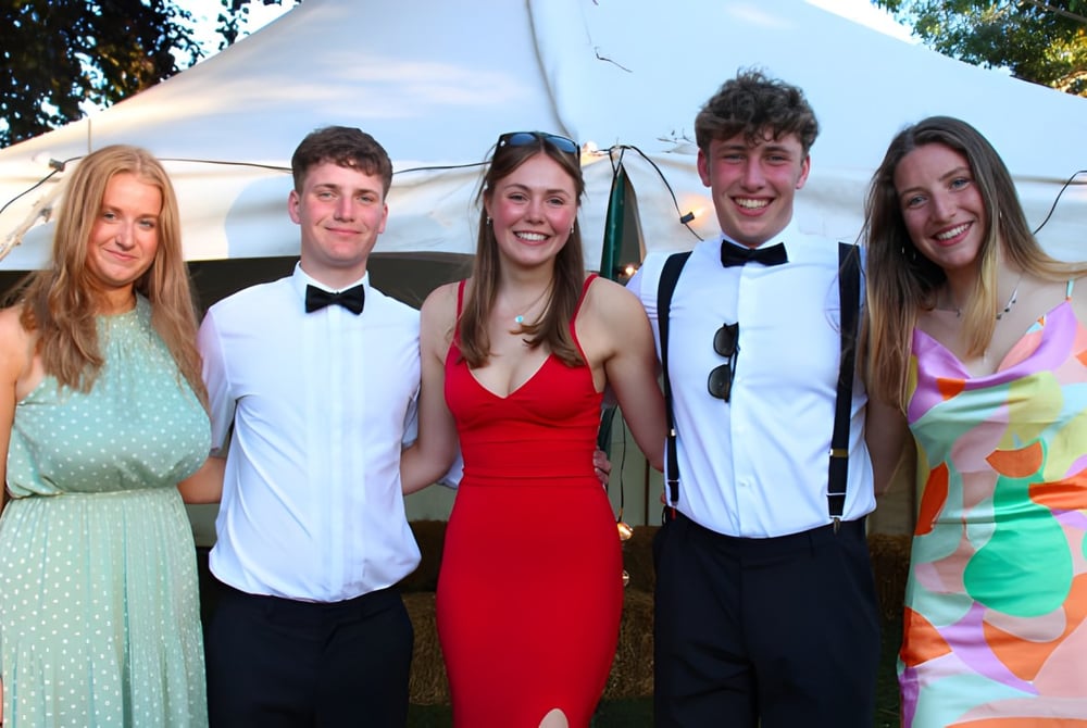 Eine Gruppe von fünf Schülern der Hereford Cathedral School steht vor einem Zelt im Freien mit Bäumen im Hintergrund.