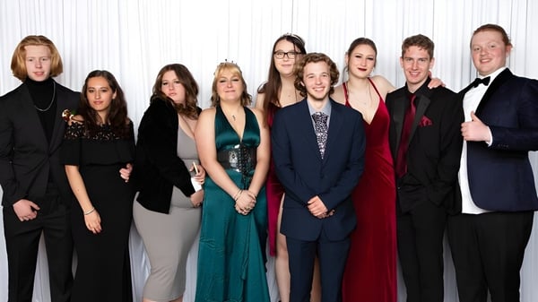 Eine Gruppe von Personen in formeller Kleidung posiert gemeinsam vor einem weißen Hintergrund am Heretaunga College.