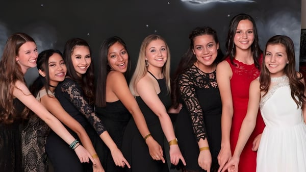 Eine Gruppe junger Frauen in formeller Kleidung posiert vor einem dunklen Hintergrund mit Mondsichel und Sternen auf dem Campus der Heritage Christian School.