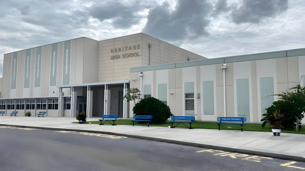 Das mehrstöckige Schulgebäude der Heritage High School mit Schriftzug an der Fassade unter bewölktem Himmel.