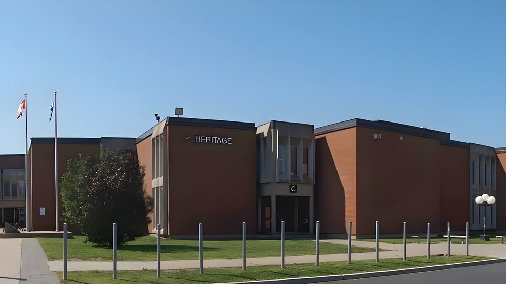 Das moderne Backsteingebäude von Heritage Regional High School mit Schriftzug und angrenzendem Grünbereich.