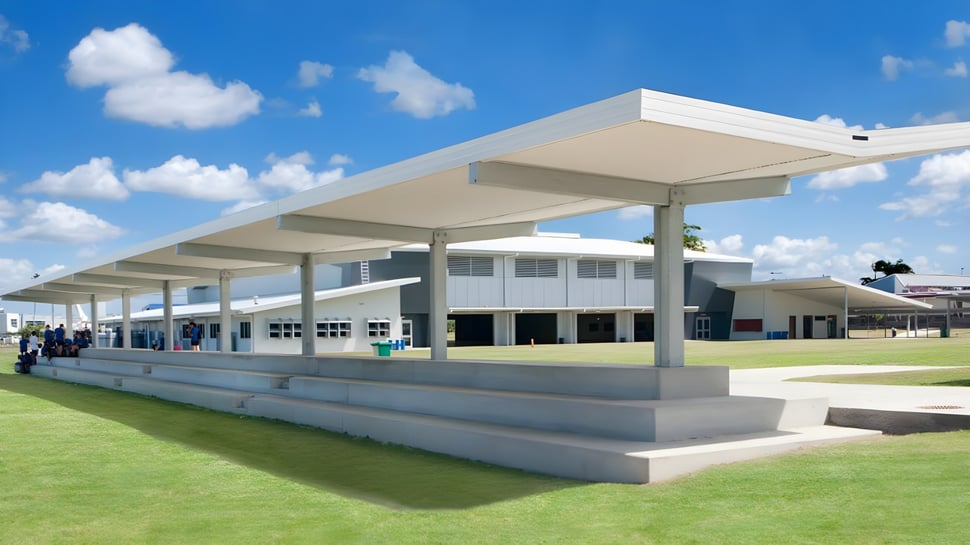 Das moderne, weiße Gebäude der Hervey Bay State High School steht auf einer Wiese unter einem blauen Himmel mit weißen Wolken.