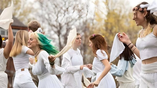 Eine Gruppe junger Frauen in weißen Kleidern steht auf einem Feld in der Natur auf dem Campus der High Mowing School.