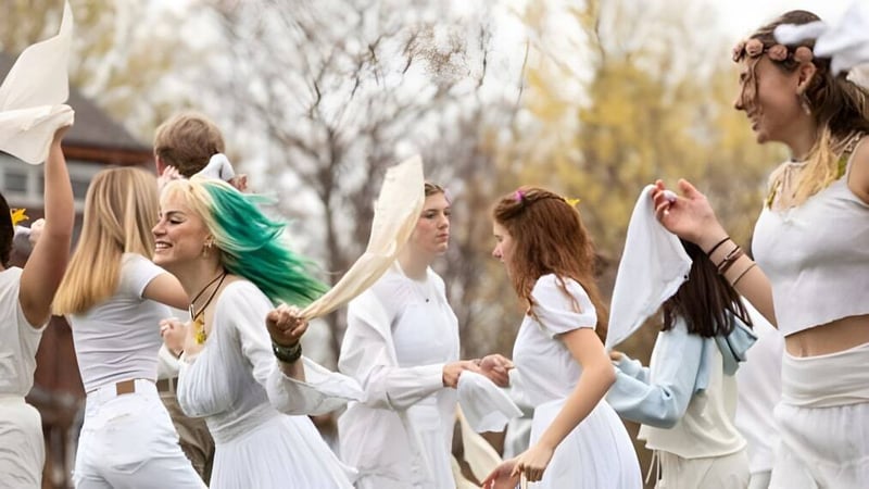 Eine Gruppe junger Frauen in weißen Kleidern steht auf einem Feld in der Natur auf dem Campus der High Mowing School.