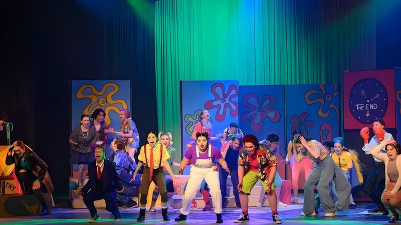 Schüler der Highland Secondary School führen eine farbenfrohe Bühnenperformance mit psychedelischem Bühnenbild auf.