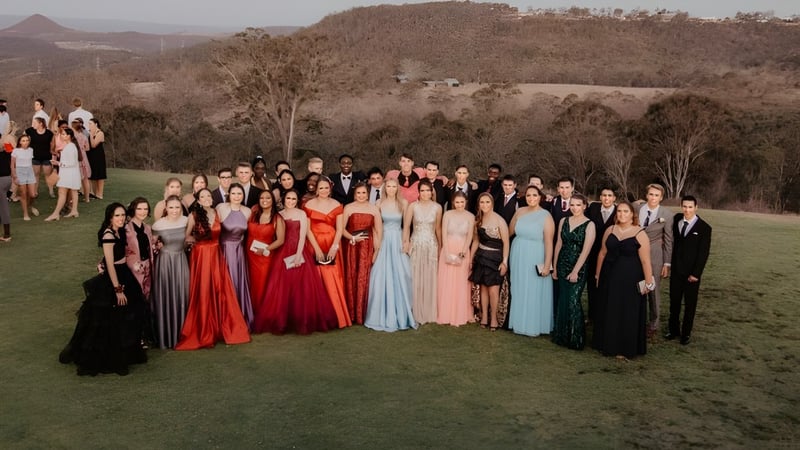 Eine große Gruppe von Schülern des Highlands Christian College steht auf einer Wiese vor einer bergigen Landschaft.