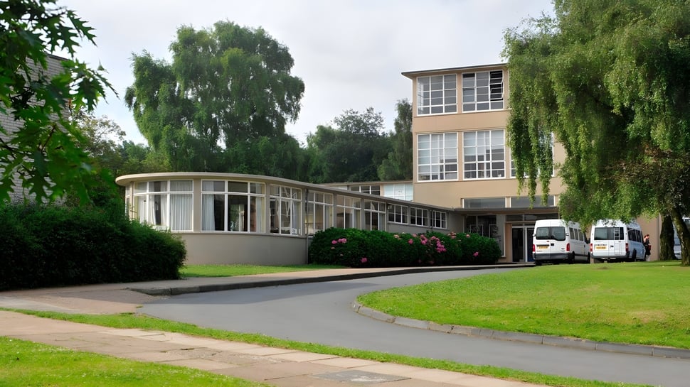 Das moderne mehrstöckige Gebäude mit geschwungener Glasfassade der Highworth Grammar School ist von grüner Landschaft umgeben.