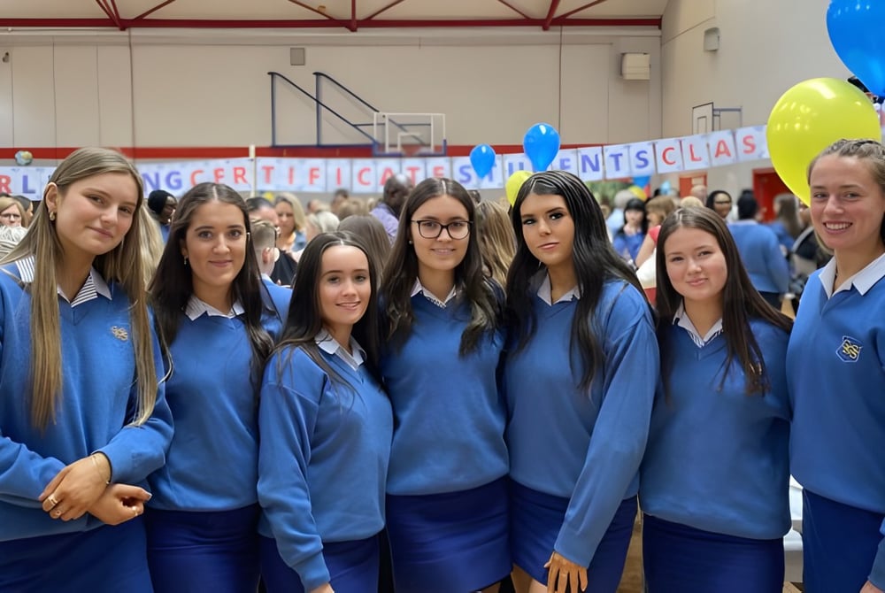 Eine Gruppe von Schülerinnen in blauen Uniformen steht zusammen bei einer Veranstaltung der Highworth Grammar School.