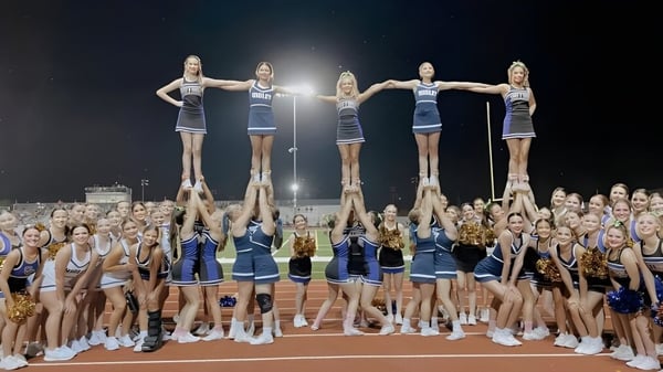 Schülerinnen der Higley High School führen auf dem Sportfeld einen Cheerleader-Stunt vor einer großen Zuschauermenge aus.