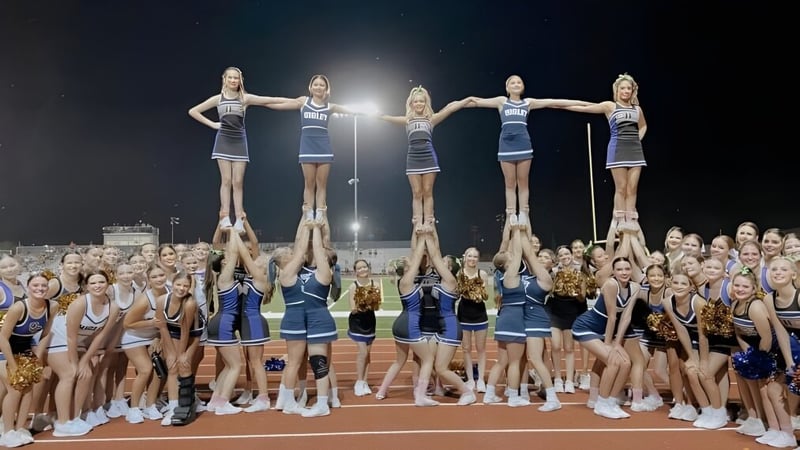 Schülerinnen der Higley High School führen auf dem Sportfeld einen Cheerleader-Stunt vor einer großen Zuschauermenge aus.