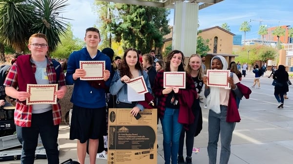 Schüler des Higley Unified School District halten im Außenbereich Urkunden in die Höhe.