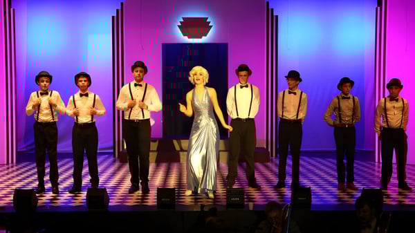 Eine Gruppe von Schülerinnen und Schülern des Hillcrest Christian College steht gemeinsam bei einem Bühnenauftritt mit bunter Beleuchtung.