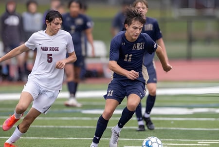 Zwei Schüler spielen Fußball auf dem Sportplatz von Hillcrest Christian College vor Zuschauern.