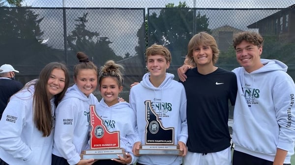 Eine Gruppe Schüler der Hillcrest High School posiert gemeinsam mit Auszeichnungen im Freien vor einem umzäunten Bereich mit Bäumen.