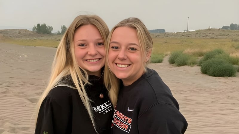 Zwei lächelnde Schülerinnen stehen in der Wüstenlandschaft mit Straßen und Sträuchern auf dem Gelände der Hillcrest High School.