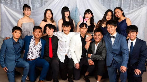 Eine Gruppe von Schülerinnen und Schülern der Hillmorton High School posiert in formeller Kleidung vor weißen Vorhängen.