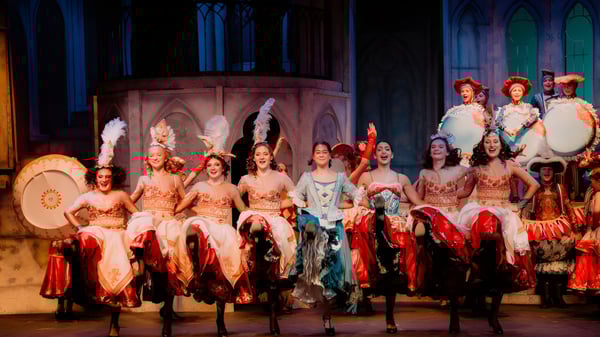 Eine Gruppe von Schülern der Hilton Head Preparatory School steht in farbenfrohen Kostümen auf der Bühne vor einer architektonischen Kulisse.