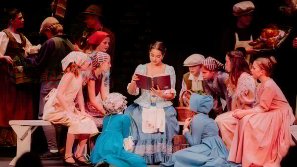 Schüler der Hilton Head Preparatory School stehen in historischen Kostümen auf einer Bühne und führen ein Theaterstück auf.