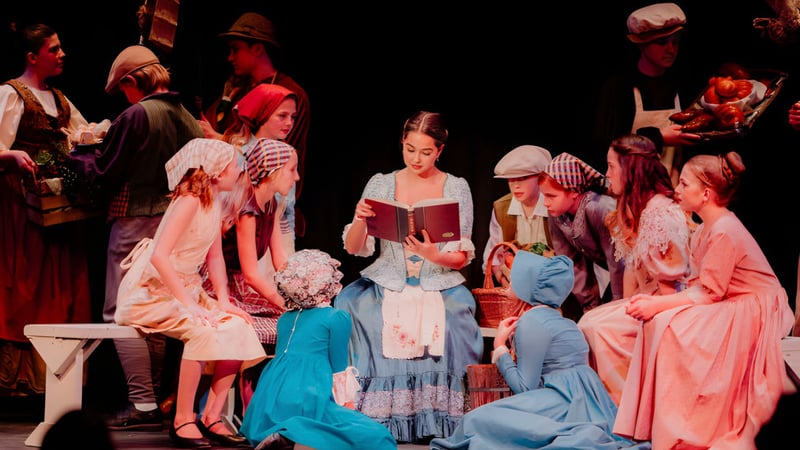 Schüler der Hilton Head Preparatory School stehen in historischen Kostümen auf einer Bühne und führen ein Theaterstück auf.