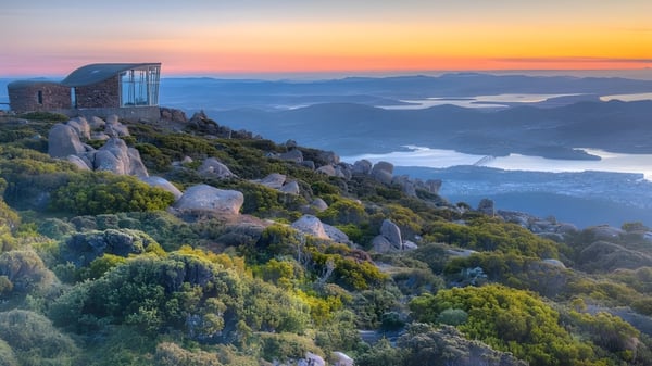 Das Glasgebäude auf einem Felsen bietet eine Aussicht auf Berge und Seen auf dem Gelände des Hobart College bei Sonnenuntergang.