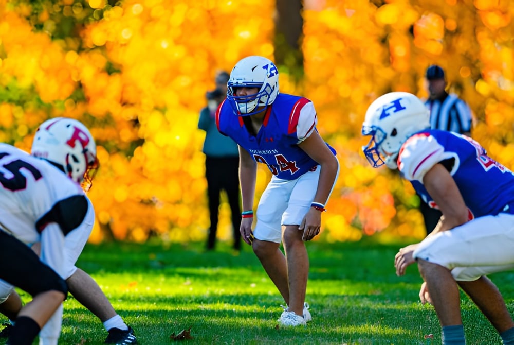 Schüler der Holderness School spielen ein Fußballspiel auf dem Spielfeld im herbstlichen Umfeld.