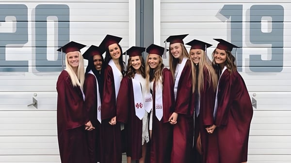 Eine Gruppe von Absolventen in roten Talaren steht vor einer Wand mit der Jahreszahl 2019 auf dem Campus der Holland Christian Schools.