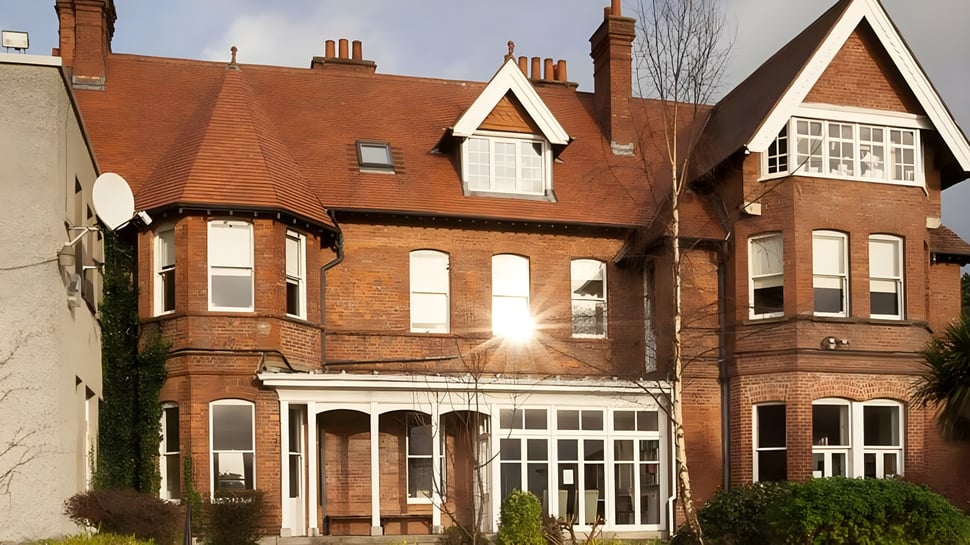 Das große Backsteingebäude der Holy Child Secondary School zeigt detaillierte Architektur und ist von grüner Vegetation umgeben.