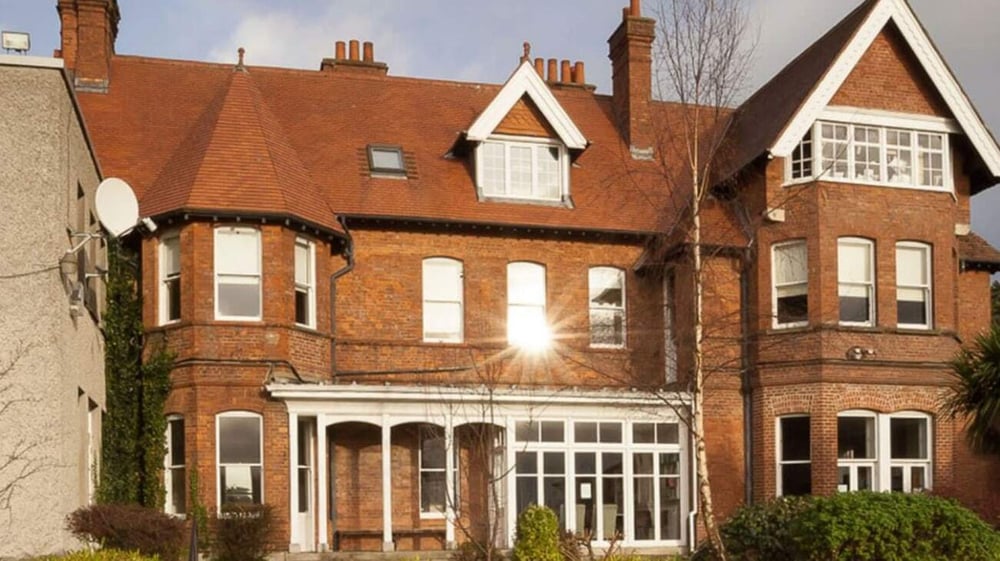 Das Backsteingebäude der Holy Child Secondary School ist von Grünflächen umgeben und wird von einem gepflasterten Weg zum Eingang ergänzt.