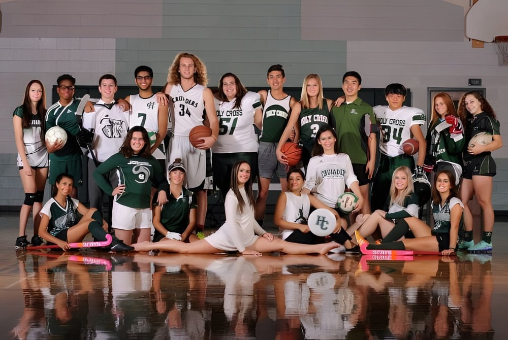 Eine Gruppe Schüler posiert auf dem Basketballplatz der Holy Cross Catholic Secondary School mit Basketballs und Sportkleidung.