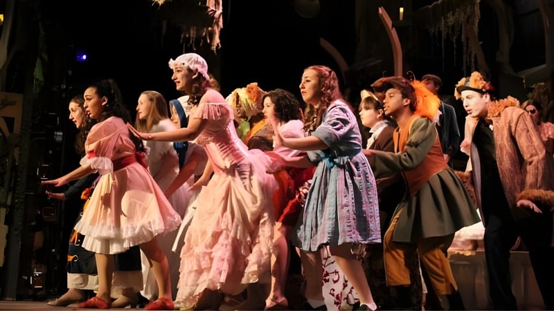 Eine Gruppe Schüler der Holy Cross High School präsentiert auf der Bühne eine bunte theatralische Szene in Kostümen.