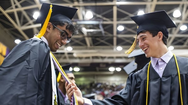 Zwei Absolventen sprechen während einer Abschlussfeier auf dem Campus der Holy Cross High School.