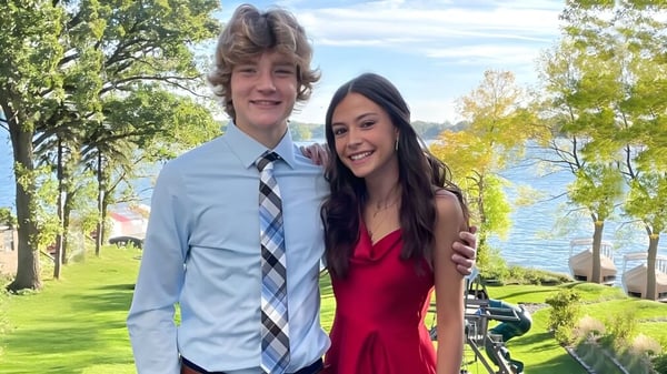 Ein junges Paar steht zusammen in einer grünen Landschaft außerhalb der Holy Family Catholic High School.