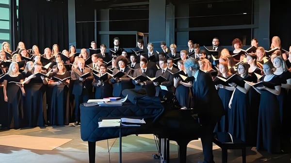 Der Chor der Holy Family Catholic High School steht in schwarzen und blauen Gewändern auf der Bühne vor einem Flügel.