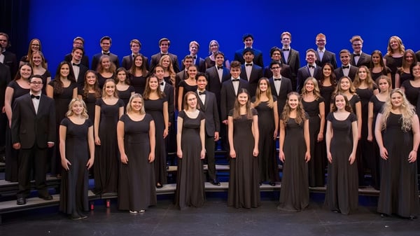 Eine Gruppe von Schülerinnen und Schülern der Holy Heart of Mary High School steht in formeller Kleidung auf einer Bühne mit blauem Hintergrund.