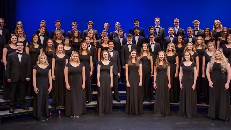Eine Gruppe von Schülerinnen und Schülern der Holy Heart of Mary High School steht in formeller Kleidung auf einer Bühne mit blauem Hintergrund.