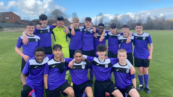 Schüler der Holy Rood High School stehen in ihren lila-gelben Trikots auf dem Fußballfeld.