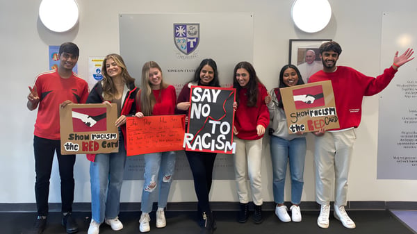 Schülerinnen und Schüler der Holy Rood High School halten Schilder bei einer Demonstration für Vielfalt und gegen Rassismus.
