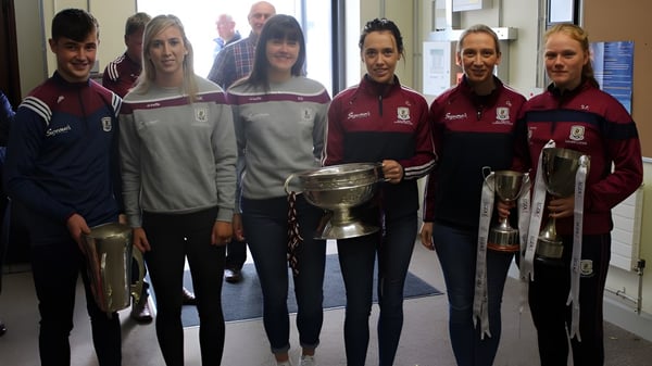 Eine Gruppe Schüler in einheitlichen Uniformen hält einen Pokal im Flur des Holy Rosary College.