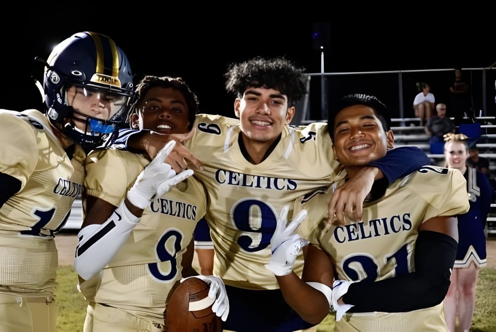 Eine Gruppe junger Footballspieler feiert gemeinsam auf dem Spielfeld der Holy Trinity Catholic High School.