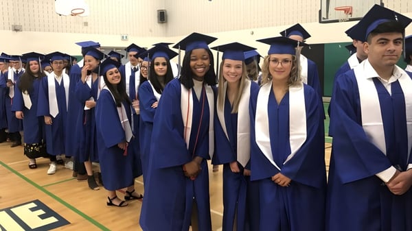 Eine Gruppe von Absolventen steht in blauen Talaren in der Aula der Holy Trinity Catholic High School.
