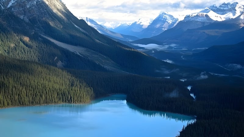 Ein türkisfarbener See umgeben von schneebedeckten Bergen und Nadelwald auf dem Gelände der Holy Trinity High School.