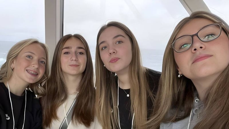 Vier Schülerinnen der Holy Trinity High School posieren vor einem Fenster mit Blick auf den bewölkten Himmel.