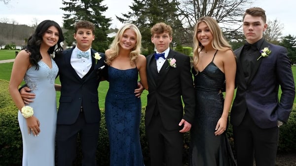 Eine Gruppe Schülerinnen und Schüler des Honourable W.C. Kennedy Collegiate posiert gemeinsam in einem parkähnlichen Außenbereich mit Bäumen.