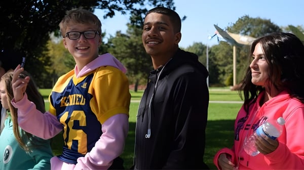 Drei Schülerinnen und Schüler stehen gemeinsam in einer parkähnlichen Umgebung auf dem Campus der Honourable W.C. Kennedy Collegiate.